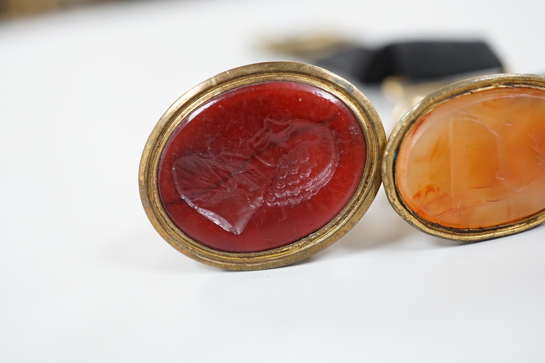 Four assorted 19th century gold plated and agate or hardstone set oval fob seals, largest 37mm, two matrices carved with busts and two with animals.